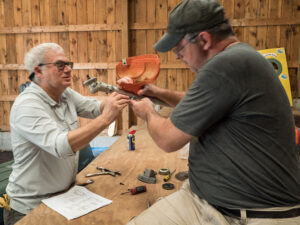 Two men setting up a brush cutting tool in the barn